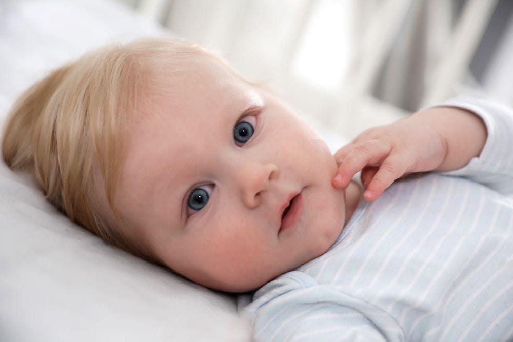 Conjunctivitis. Little baby with red eyes in bed, closeup