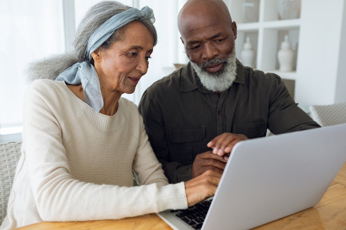 An elderly couple use a laptop