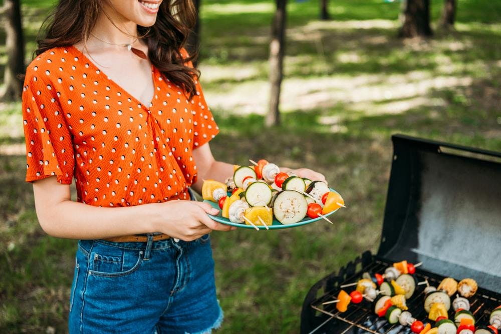 A woman grilling vegetables in an outdoor grill