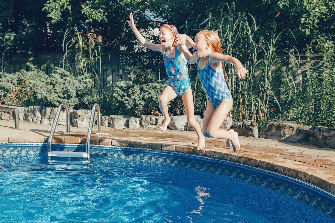 Two young children jumping into a pool