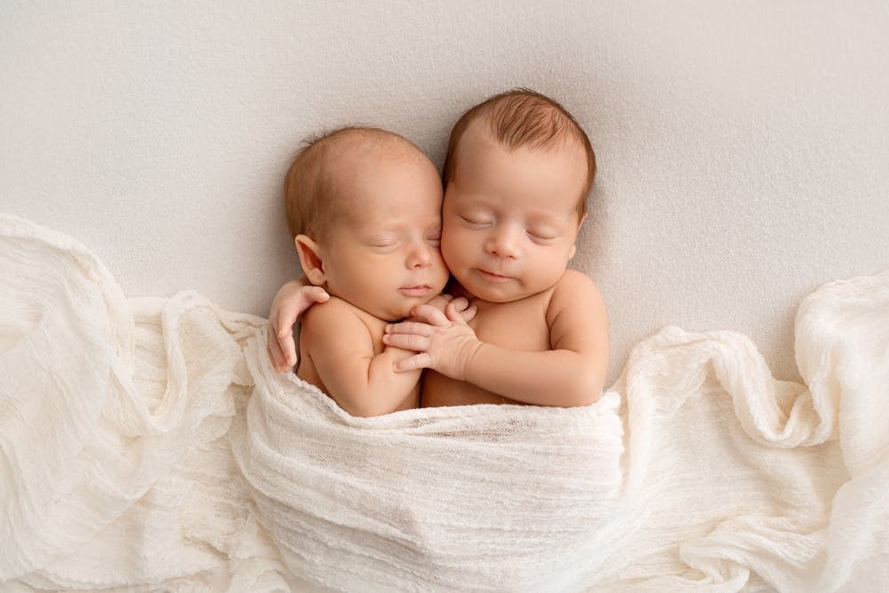 Two newborn babies hugging each other 