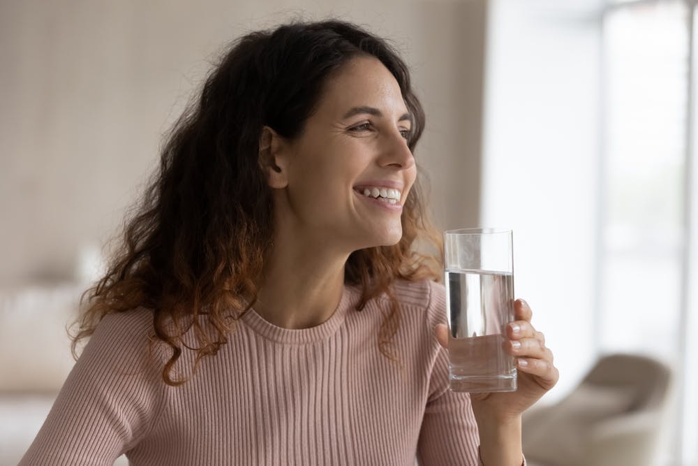 A smiling young woman drinking water