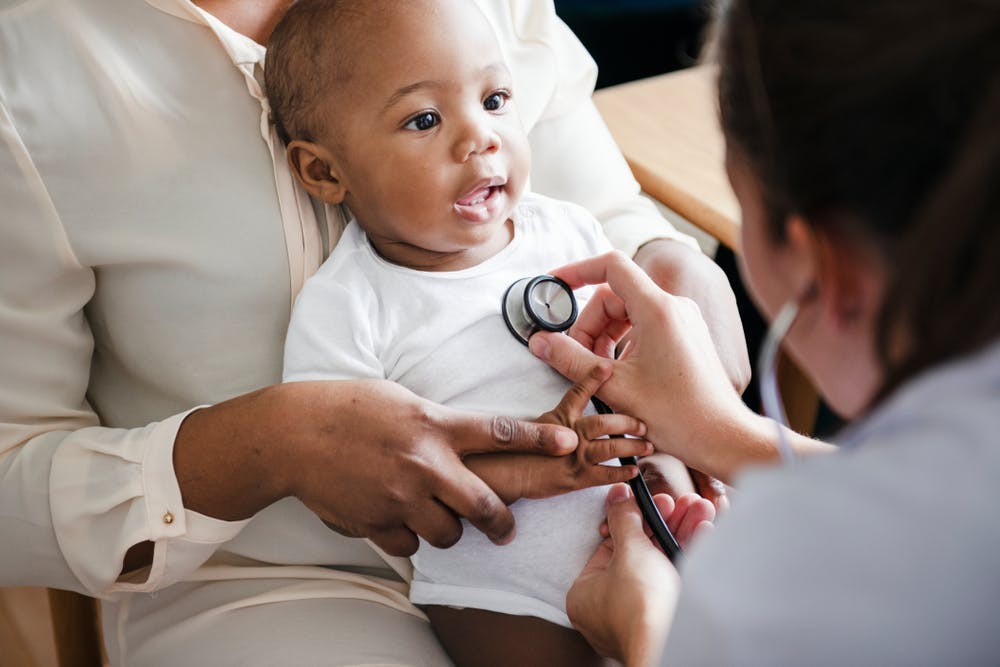 A baby is seen by a doctor